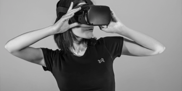 Black and white portrait of a young woman using a VR headset.