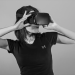 Black and white portrait of a young woman using a VR headset.