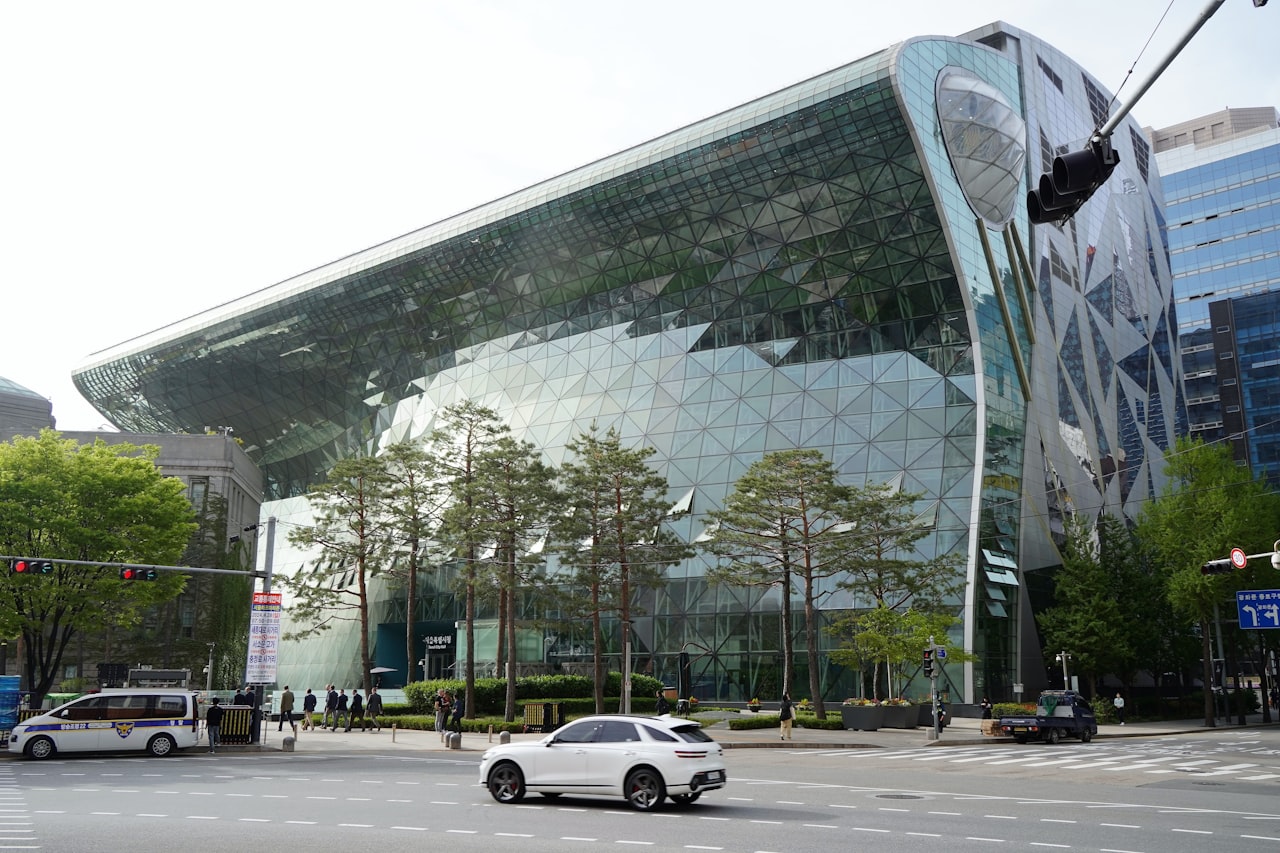 A car driving past a large building on a city street