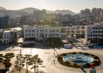 white and blue round fountain in the middle of city buildings during daytime