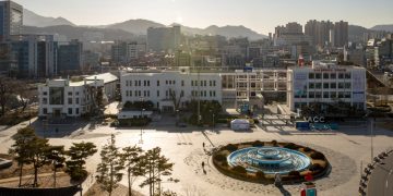 white and blue round fountain in the middle of city buildings during daytime