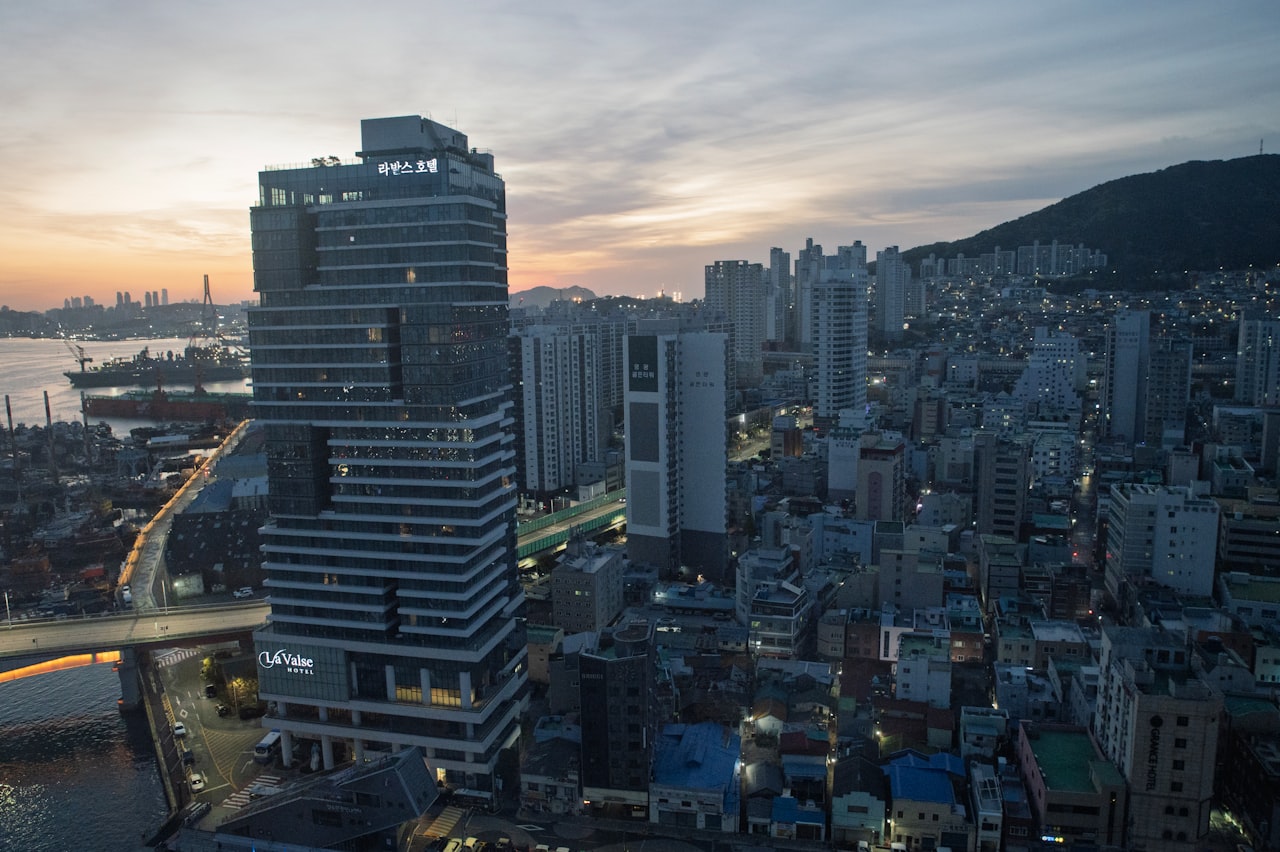 Modern skyscraper in a dense urban cityscape at dusk.