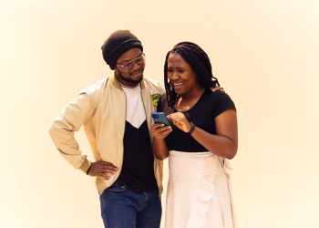 A joyful moment between a couple sharing a fun interaction over a smartphone.