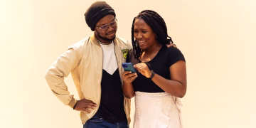 A joyful moment between a couple sharing a fun interaction over a smartphone.