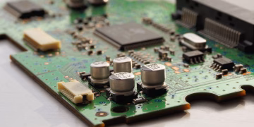 Detailed view of a green circuit board featuring capacitors and microchips.