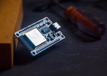 Microcontroller chip with screwdriver on dark surface, ideal for tech and innovation themes.