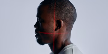 Side profile portrait of an adult man with laser scanning lines on face, showcasing advanced recognition technology.