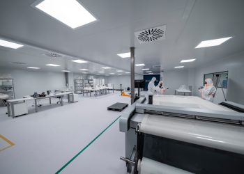 Workers are inside a clean room manufacturing something.