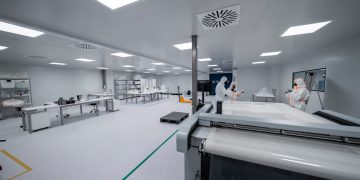 Workers are inside a clean room manufacturing something.