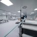 Workers are inside a clean room manufacturing something.