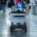 Autonomous delivery robot navigating indoors during a technology event.
