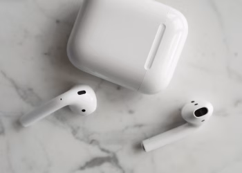 High-quality image of wireless earbuds and charging case on marble surface, showcasing modern technology.