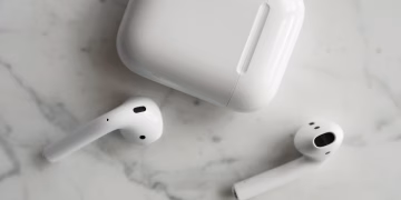 High-quality image of wireless earbuds and charging case on marble surface, showcasing modern technology.
