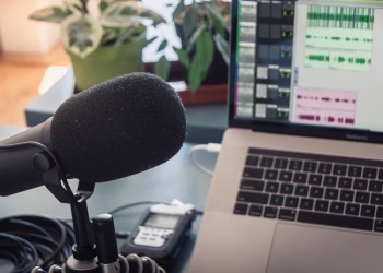 A podcast recording setup with a laptop, microphone, and audio equipment indoors.
