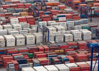 Aerial view of a bustling port with colorful cargo containers arranged in rows, showcasing logistics and trade.