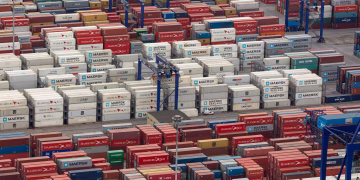 Aerial view of a bustling port with colorful cargo containers arranged in rows, showcasing logistics and trade.