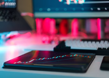 High-tech trading setup with charts on tablet and computer screens, representing data analysis and financial trends.