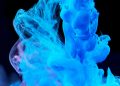Dynamic blue ink swirls in water creating abstract shapes on a dark backdrop.