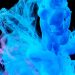 Dynamic blue ink swirls in water creating abstract shapes on a dark backdrop.