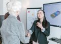 Professional women shaking hands in a corporate office setting, symbolizing a successful business agreement.