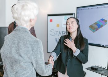 Professional women shaking hands in a corporate office setting, symbolizing a successful business agreement.
