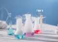 Brightly colored laboratory flasks emitting steam on a table, showcasing scientific exploration.