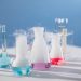 Brightly colored laboratory flasks emitting steam on a table, showcasing scientific exploration.