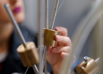 A student conducting an interactive physics experiment with brass components.