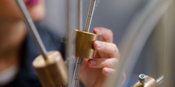 A student conducting an interactive physics experiment with brass components.