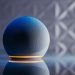 Close-up of a modern smart speaker in a stylish setting with illuminated base and reflection.