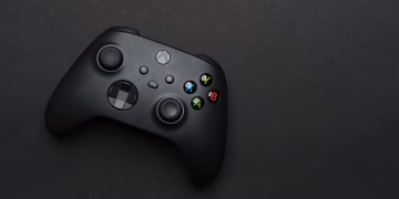 Closeup of a black gaming controller on a dark backdrop, perfect for tech themes.