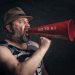 Bearded man shouting through a red megaphone with 'No to A.I' message.