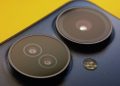 Extreme close-up of smartphone camera lenses with vibrant yellow background, showcasing modern technology.