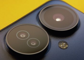 Extreme close-up of smartphone camera lenses with vibrant yellow background, showcasing modern technology.