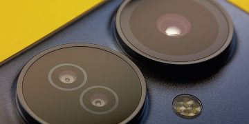 Extreme close-up of smartphone camera lenses with vibrant yellow background, showcasing modern technology.