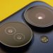 Extreme close-up of smartphone camera lenses with vibrant yellow background, showcasing modern technology.