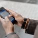 Close-up of hands with bracelets navigating on smartphone using GPS app outdoors.