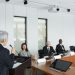 A diverse group of professionals engaging in a business meeting in a conference room with a speaker at the podium.