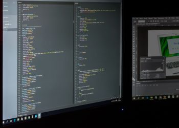 A dual screen setup showcasing programming code and image editing software.