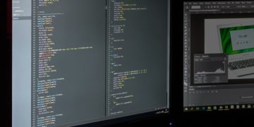 A dual screen setup showcasing programming code and image editing software.