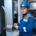 Industrial engineer in safety gear working on a CNC machine in a modern factory setting.