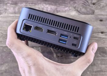 Close-up of a compact computer showing various ports held in a person's hand.
