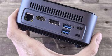 Close-up of a compact computer showing various ports held in a person's hand.