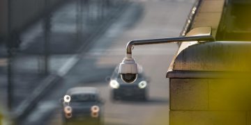 CCTV camera overlooking a busy street with cars in motion, capturing urban surveillance.