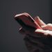 Close-up of hands holding a smartphone in dim lighting, showcasing texting or browsing activity.