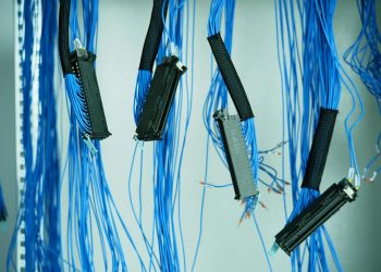 Close-up of blue ethernet cables hanging in a data center, highlighting technology connections.