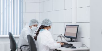Two scientists at a computer in a laboratory setting, analyzing data with focus and precision.