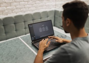 A man working on a laptop in a cozy, modern office space with a focus on technology.