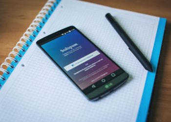 A smartphone displaying Instagram on a notepad with a pen, symbolizing social media and productivity.