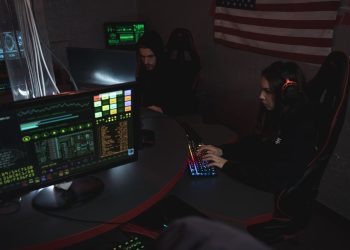 Cybersecurity professionals working on computer systems, focusing on data protection in a dimly lit room.